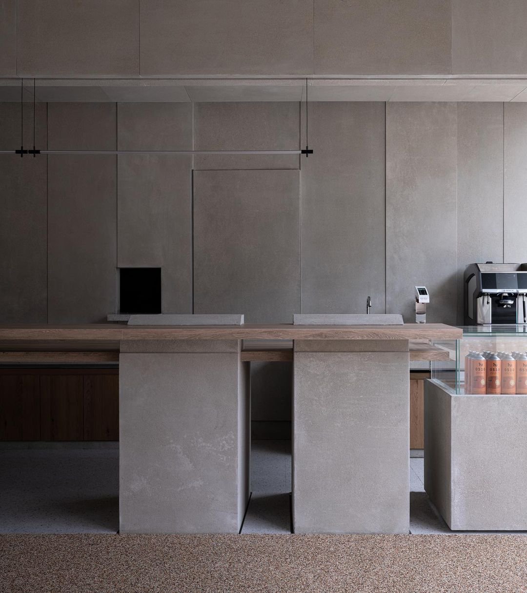 The tank displays flank the bar, both embedded within a sweeping C-shaped concrete beam that spans across the space. Here, t...